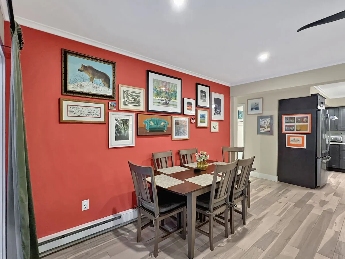 A warm, welcoming dining space highlighted by a central table adorned with a flower vase, surrounded by art-filled walls. The ambiance is perfect for family meals, social gatherings, and fostering connections among residents.